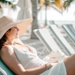 Woman in wide-brimmed hat relaxing in shade at sunny Florida beach protecting her skin after waxing