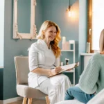 A mother and teen daughter speaking with a friendly aesthetician in a clean bright waxing salon