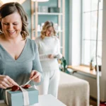 Woman smiling as she unwraps a gift box in a bright, clean waxing salon