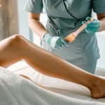 Technician applying wax to a client's leg for a full leg and Brazilian wax package.
